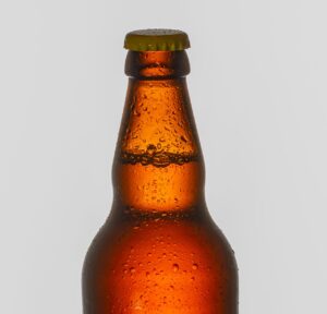 High-resolution close-up of a chilled beer bottle with water droplets against a neutral background.